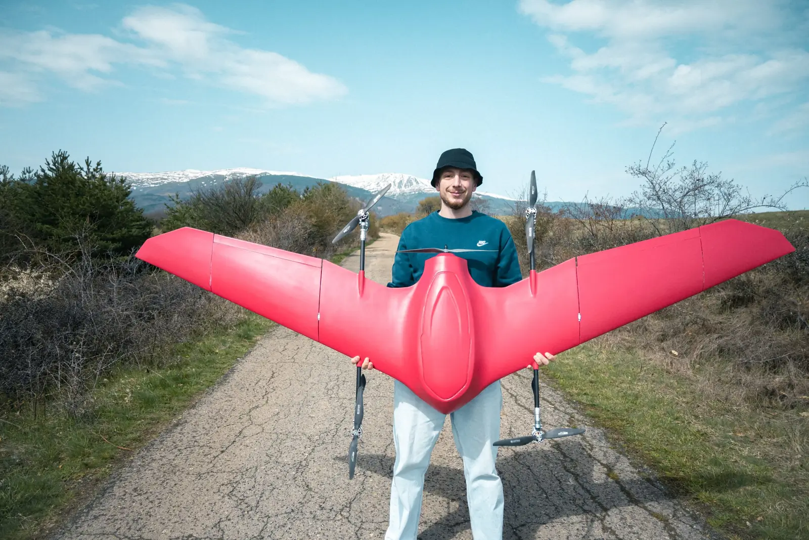 مشغّل يرفع طائرة Nimbus الحمراء VTOL فوق رأسه، بكامل باع الجناح أمام السماء