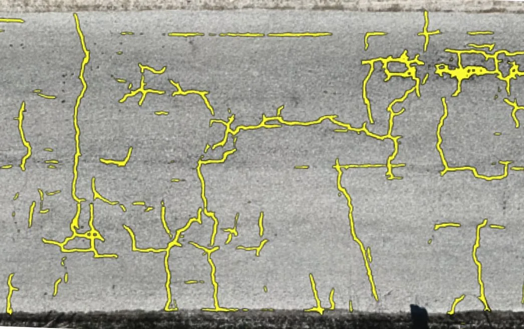 Asphalt orthomosaic with HALO AI crack segmentation traced in yellow over the surface